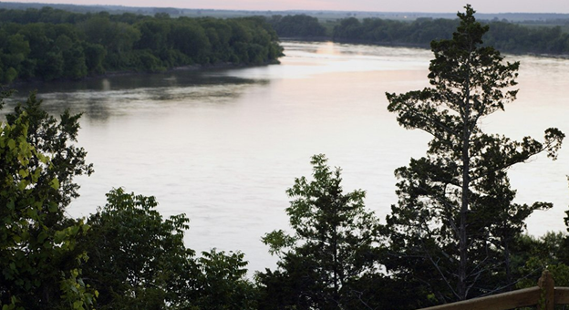 A beautiful view of the tree lined Missouri River at sunrise from atop a bluff. 